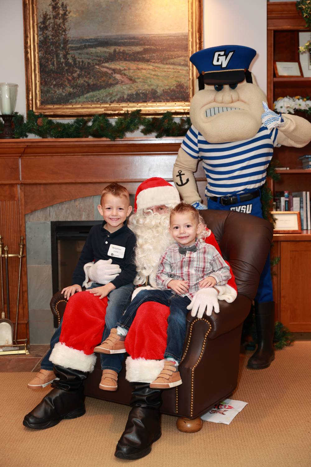 Two boys sitting with Santa & Louie at the event.